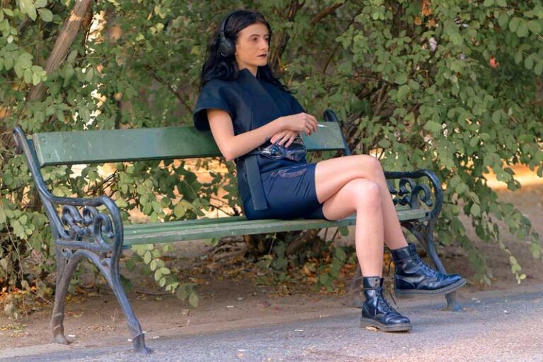Woman sitting on a park bench, listening to music